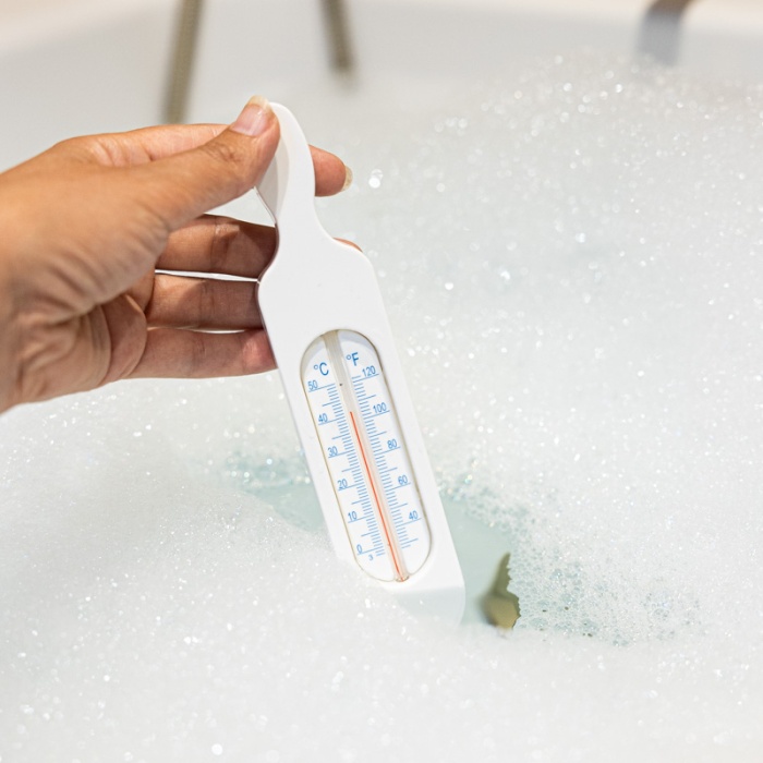 White bath thermometer taking bath water temperature