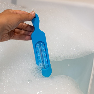 Blue bath thermometer taking bath water temperature