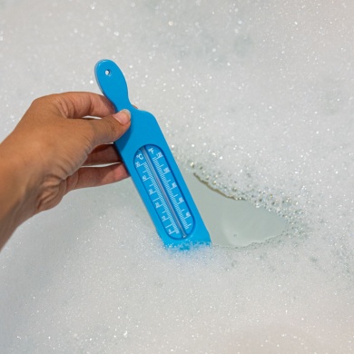 Blue bath thermometer taking bath water temperature