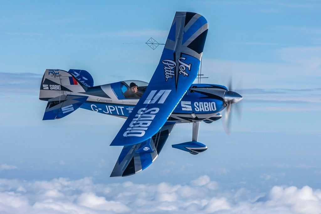 Blue G-EWIZ biplane flying across a blue sky