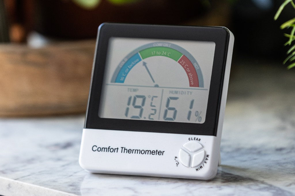 ETI comfort thermometer sitting on marble countertop with plants blurred in background