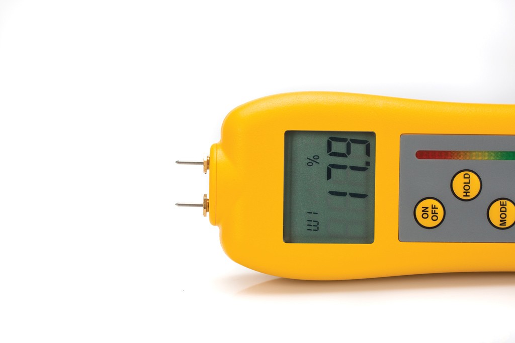 A pin type moisture meter lying sideways on a plain white background