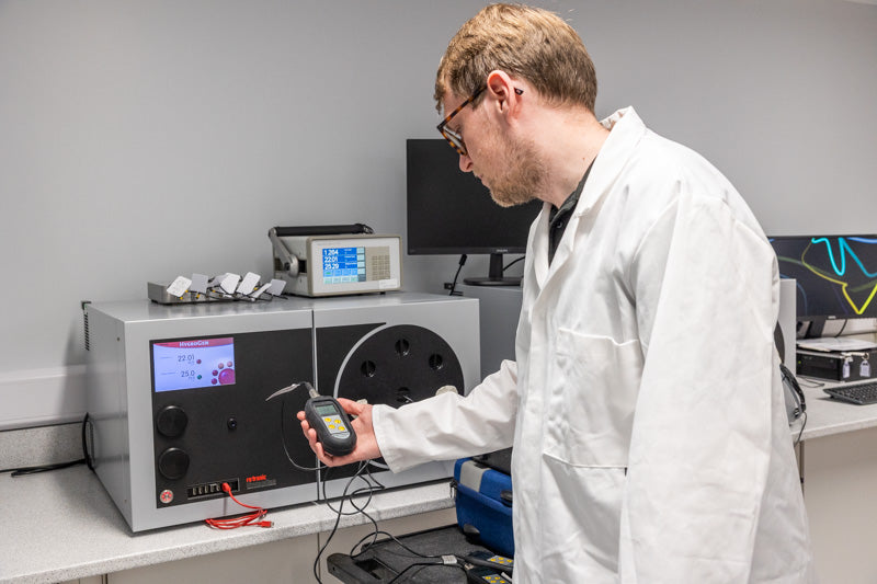 Person in a lab coat using electronic equipment in a laboratory setting