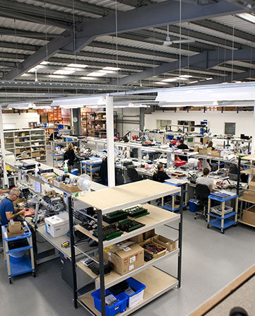 Industrious warehouse with employees working at desks and shelves stocked with items.