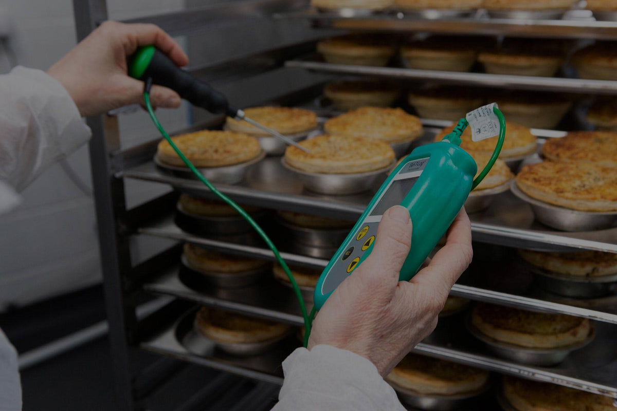 Digital thermometer testing the temperature of a pie on a metal rack