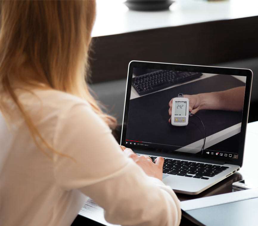 Person using a laptop with a video on the screen showing a hand holding a thermometer.