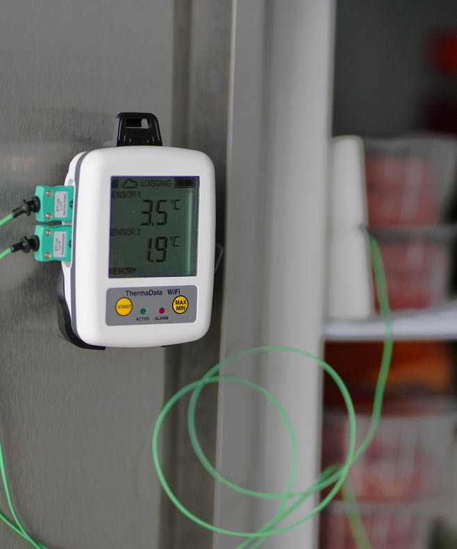 Digital thermometer attached to a wall with a blurred background