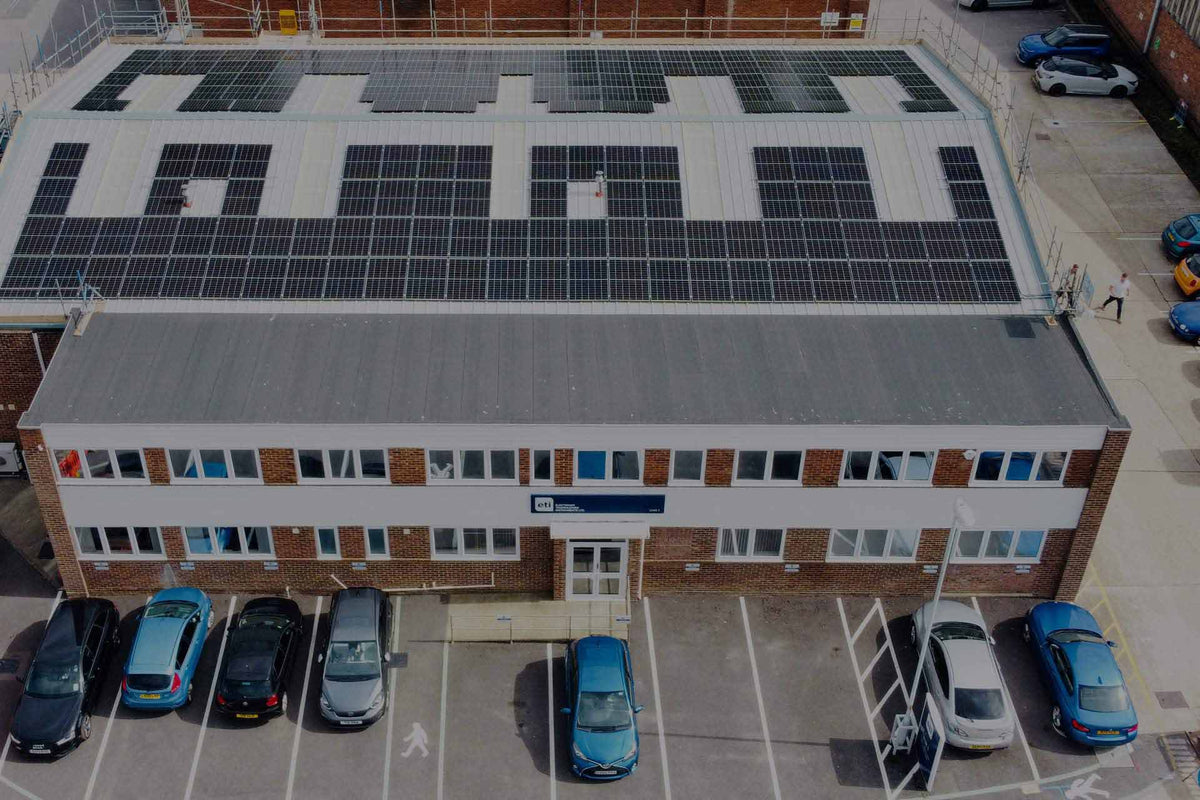 Building with solar panels on the roof and parked cars below