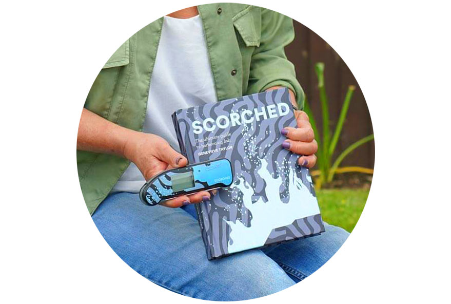 Close up image in a circle with hands holding the Scorched book and matching custom design Thermapen ONE