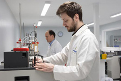 Two males workin in calibration laboratory wearing white robes